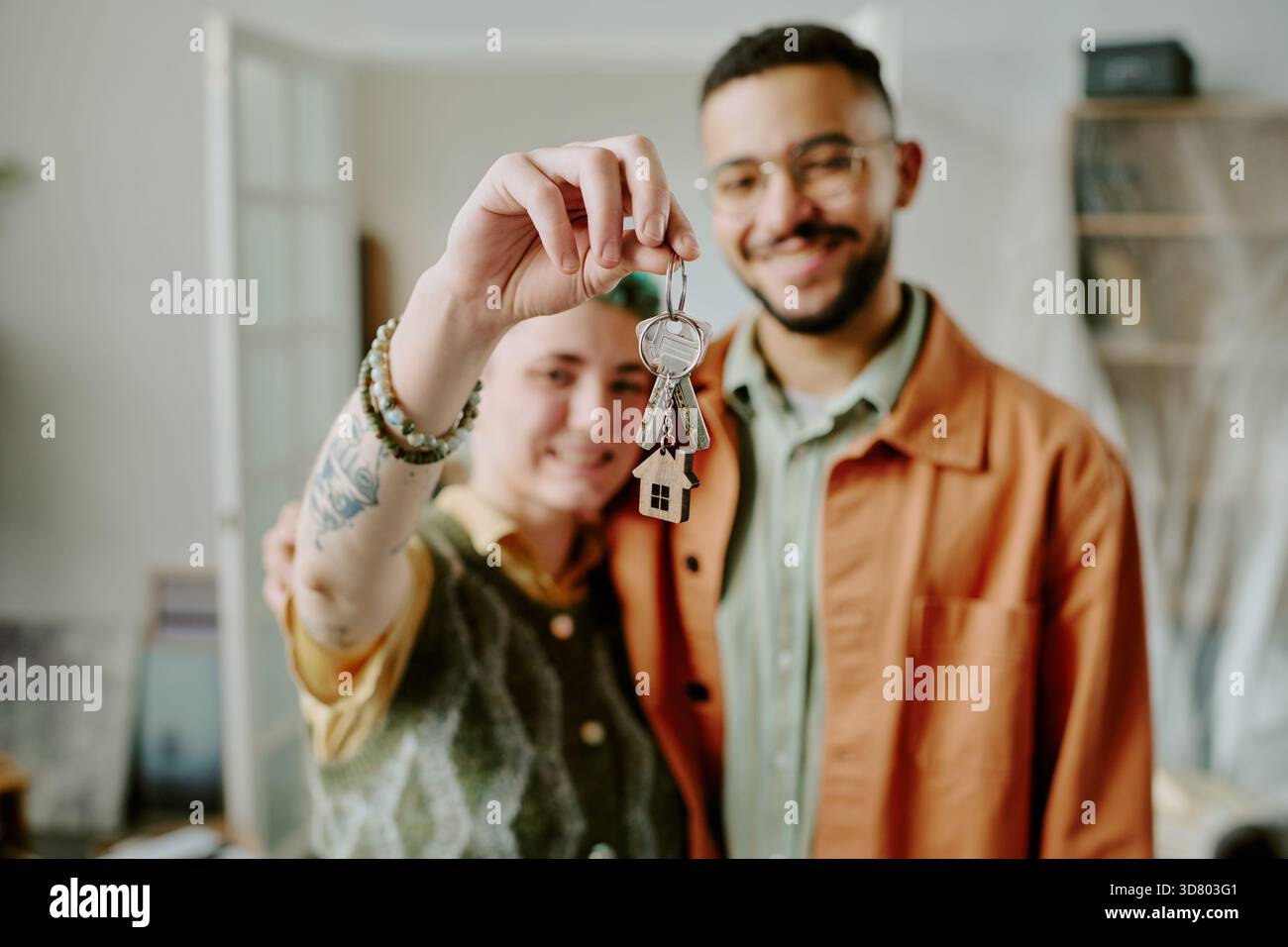Jeune couple tenant Keys souriant tout en emménageant dans la nouvelle maison Banque D'Images