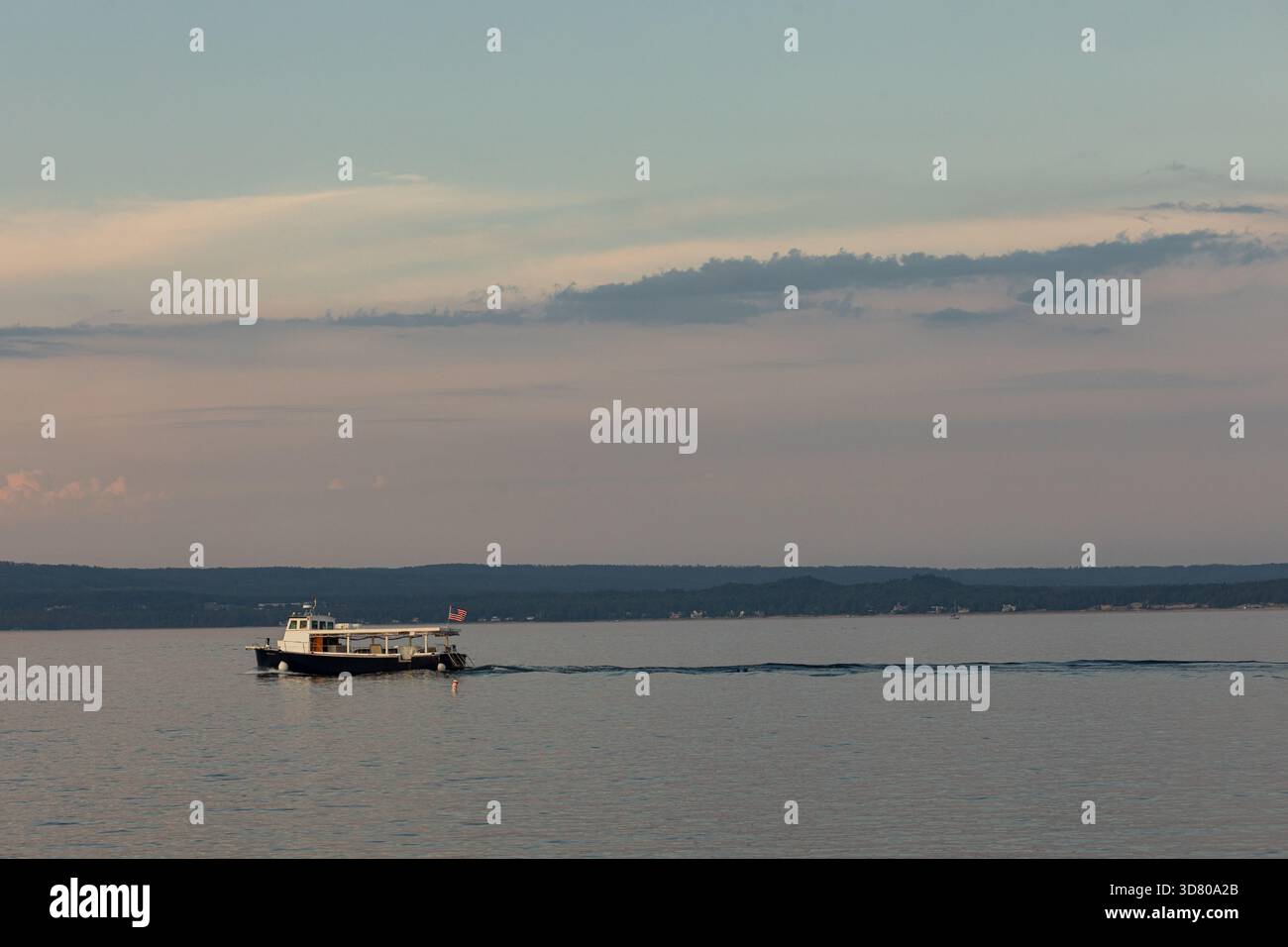 Petit ferry naviguant sur des eaux calmes dans la soirée Banque D'Images