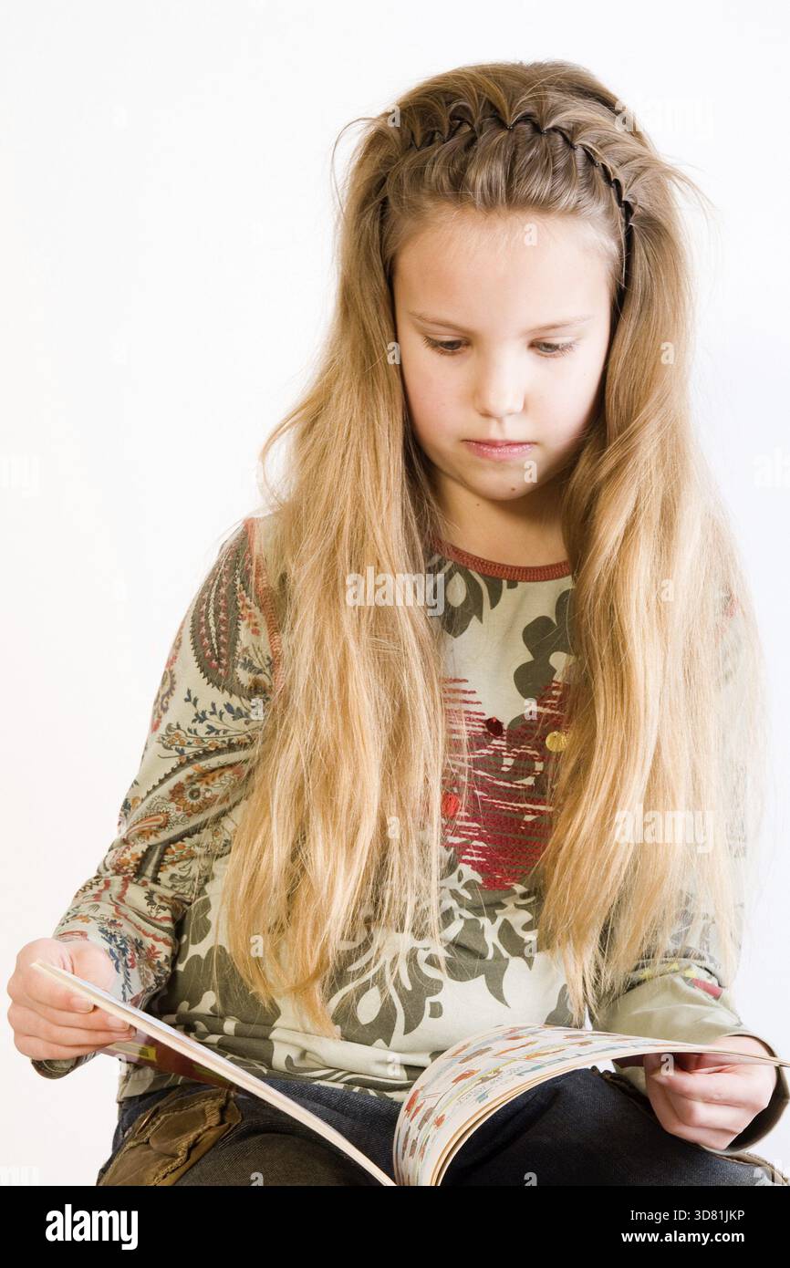 Portrait en studio d'un enfant blond lisant un livre Banque D'Images