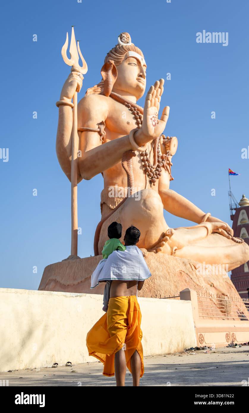 chercheur spirituel honorant une sculpture divine colossale contre un horizon calme et sans nuages Banque D'Images