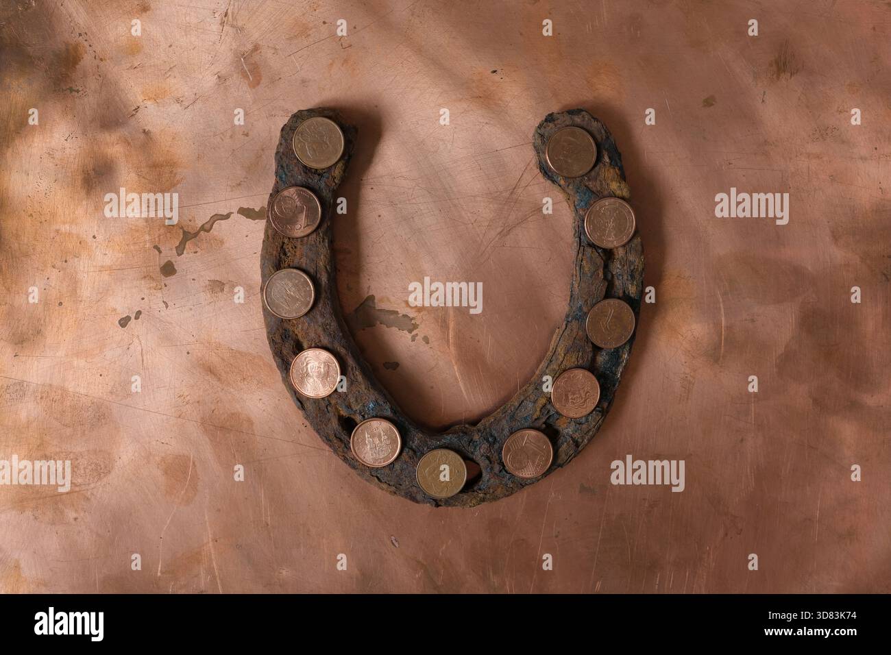 Pièces d'un centime d'euro en acier plaqué cuivre placées sur le vieux fer à cheval rouillé. Rugosité, irrégularités, défauts de texture du cuivre. Banque D'Images