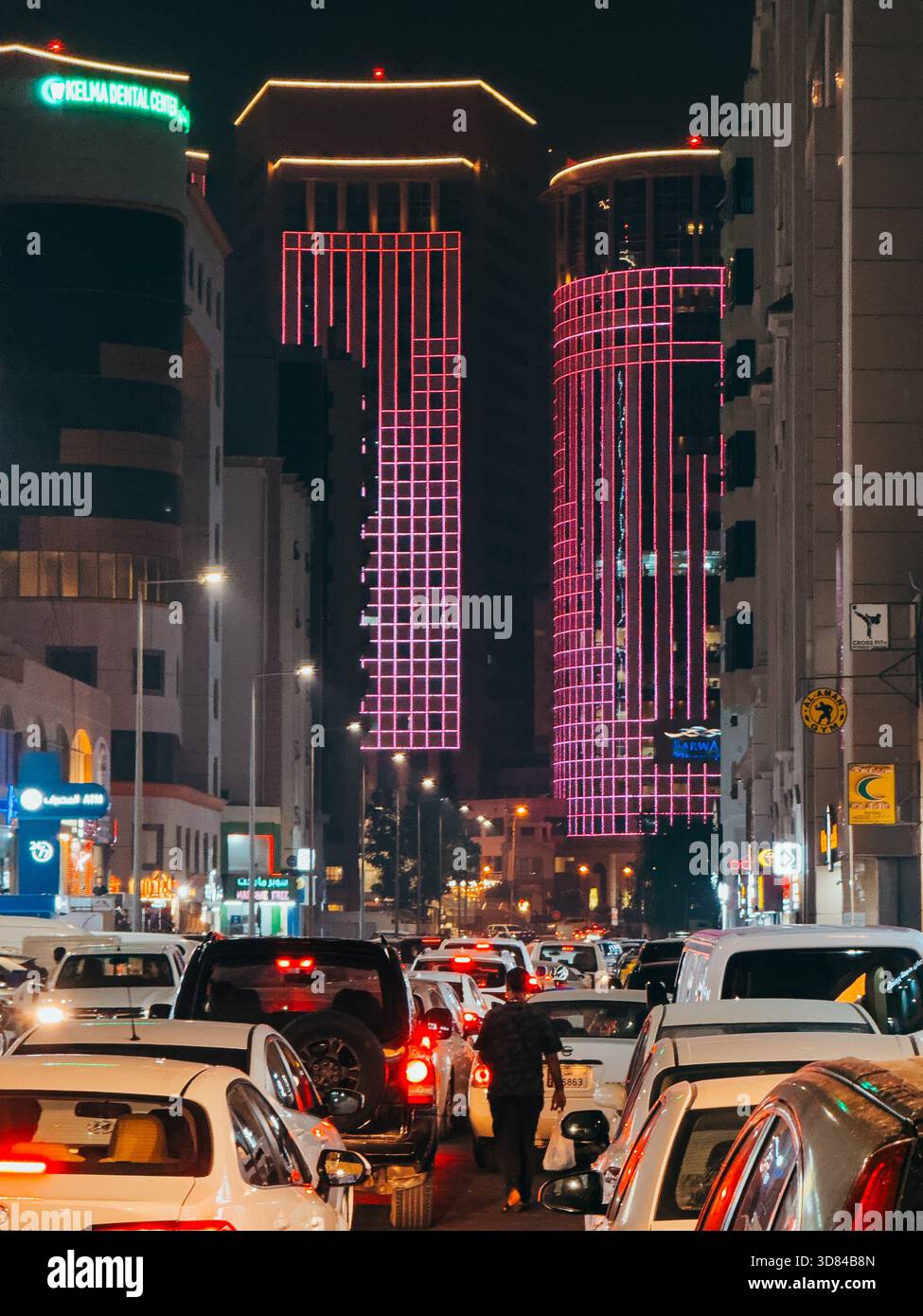 Circulation nocturne sur la rue Al Jazeera à Doha, Qatar, avec des gratte-ciel roses illuminés et des voitures denses créant une scène urbaine dynamique Banque D'Images