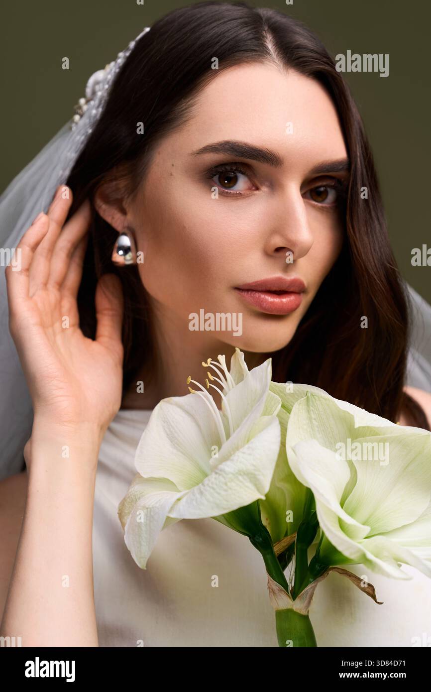 Jeune mariée met en valeur la beauté et la joie tout en tenant des fleurs délicates, rayonnant de bonheur et d'amour. Banque D'Images