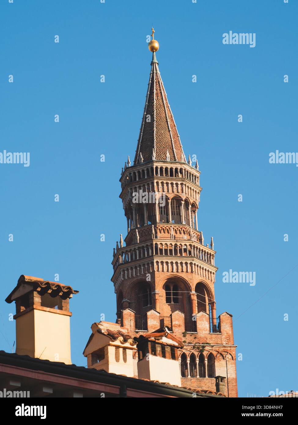 Crémone, Italie 3 octobre 2025 Torrazzo Campanile, une structure historique importante, surplombant les toits traditionnels et les cheminées sous un cl lumineux Banque D'Images