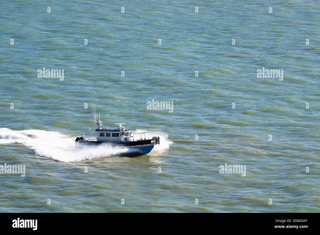 Un bateau-pilote traverse le chenal à plein régime, dégageant un jet blanc brillant contre le bleu profond alors qu'il avance à la vitesse pour rencontrer un cr entrant Banque D'Images