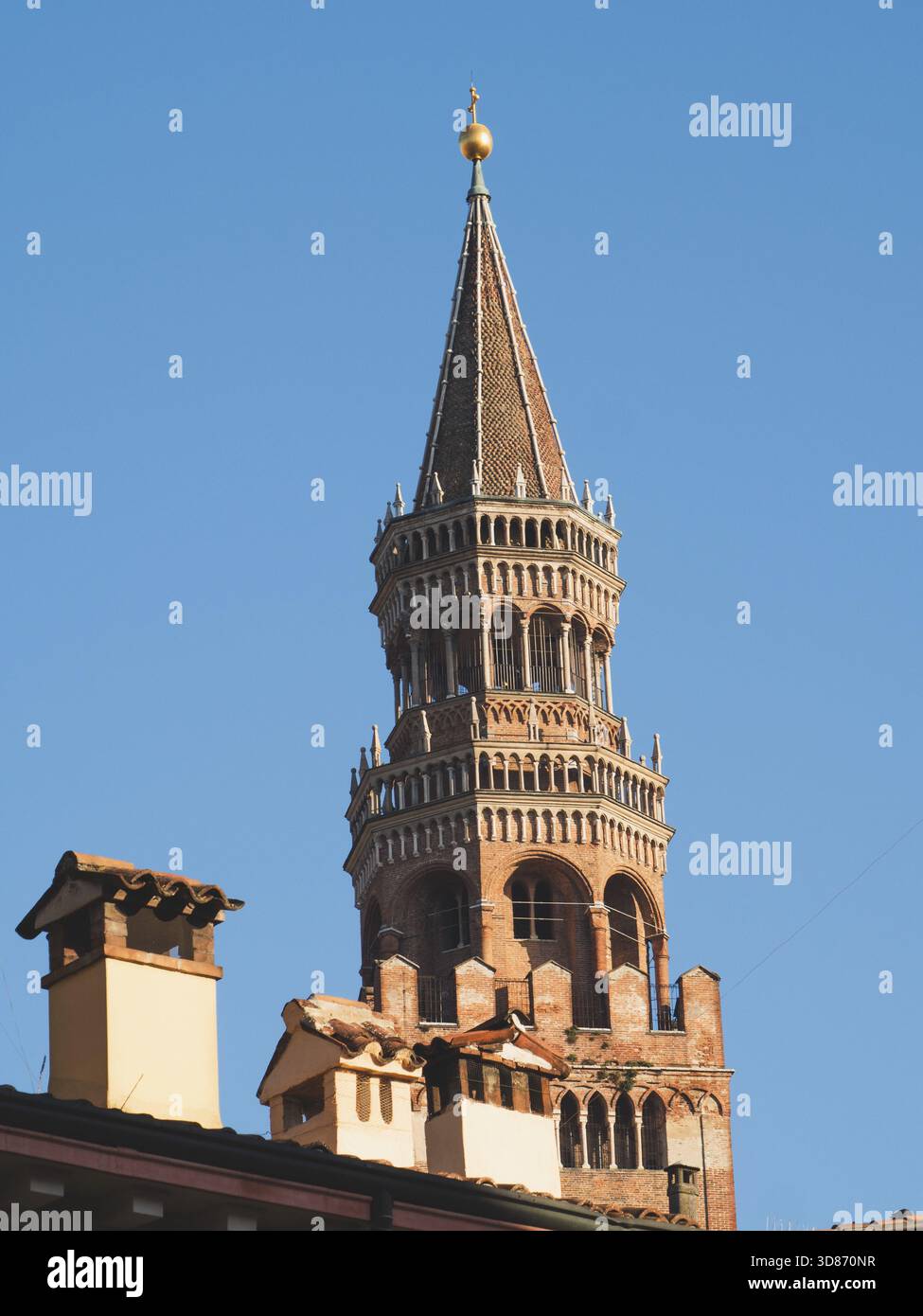 Crémone, Italie 3 octobre 2025 Torrazzo Campanile, une structure historique importante, surplombant les toits traditionnels et les cheminées sous un cl lumineux Banque D'Images