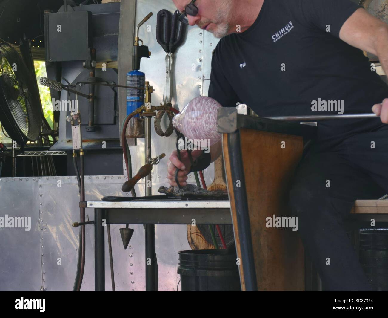 SEATTLE - APR 25, 2025 - souffleur de verre façonnant soigneusement un morceau de verre fondu à l'aide d'outils spécialisés, démontrant l'art et l'habileté impliqués Banque D'Images