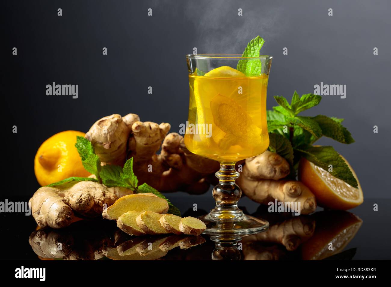 Thé au gingembre au citron et à la menthe sur un fond réfléchissant noir. Banque D'Images