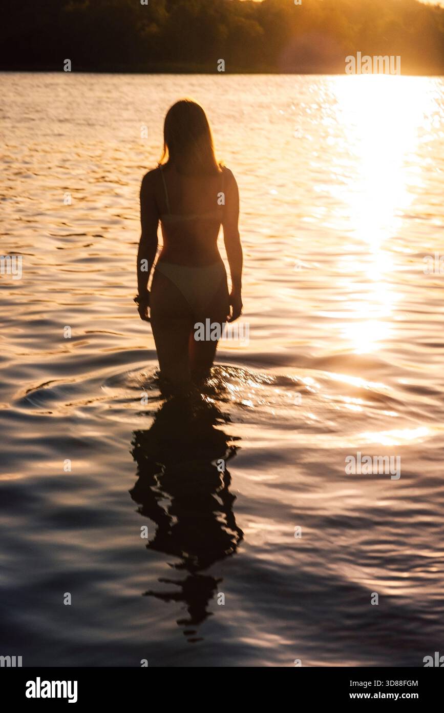 Photo en silhouette d'une femme debout dans l'eau du lac tout en regardant la vue Banque D'Images