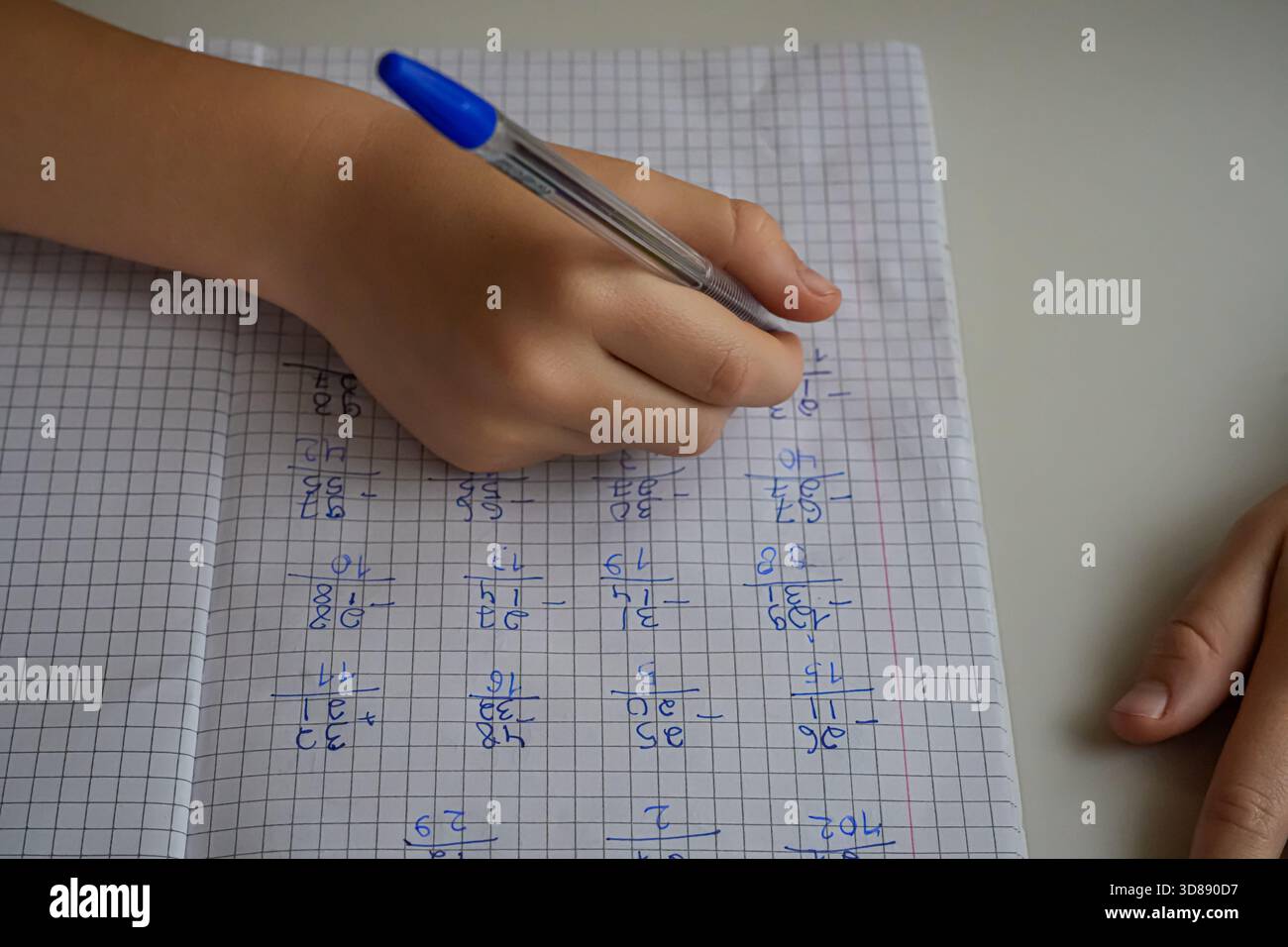 Gros plan d'une main tenant un stylo et écrivant dans un cahier avec des exemples. Face non visible. Concentrez-vous sur les études, les devoirs et l'apprentissage. Banque D'Images
