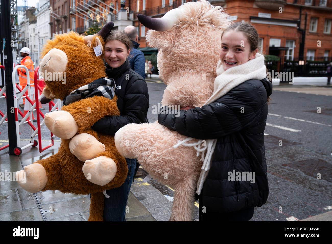 Centre de londres. Deux jeunes femmes avec des vaches massives peluches des Highland en peluche de Winter Wonderland. Banque D'Images