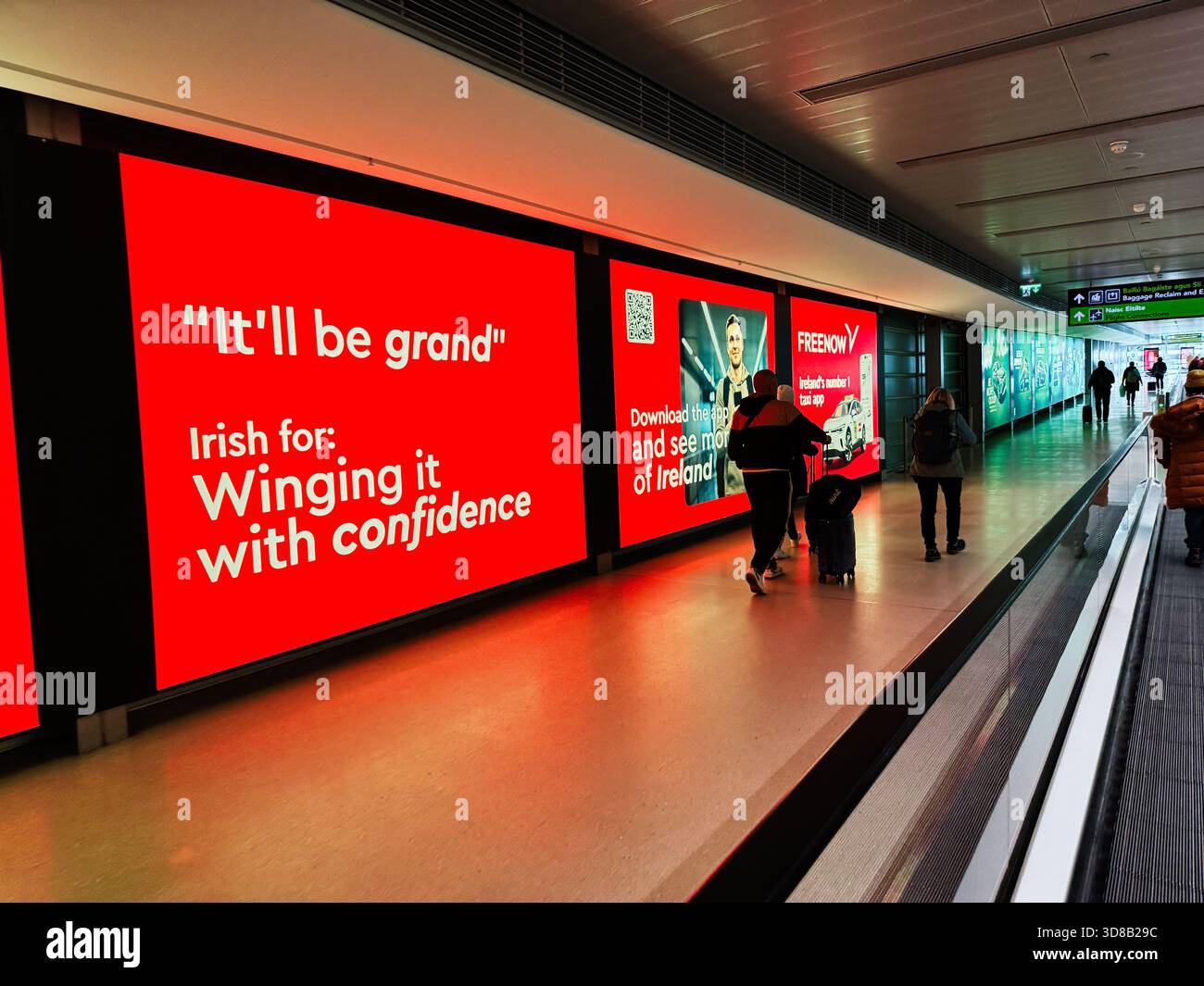 Dublin, Irlande - 21 octobre 2025 : terminal de l'aéroport de Dublin très fréquenté avec des publicités rouges audacieuses, des allées mobiles et des voyageurs. Banque D'Images