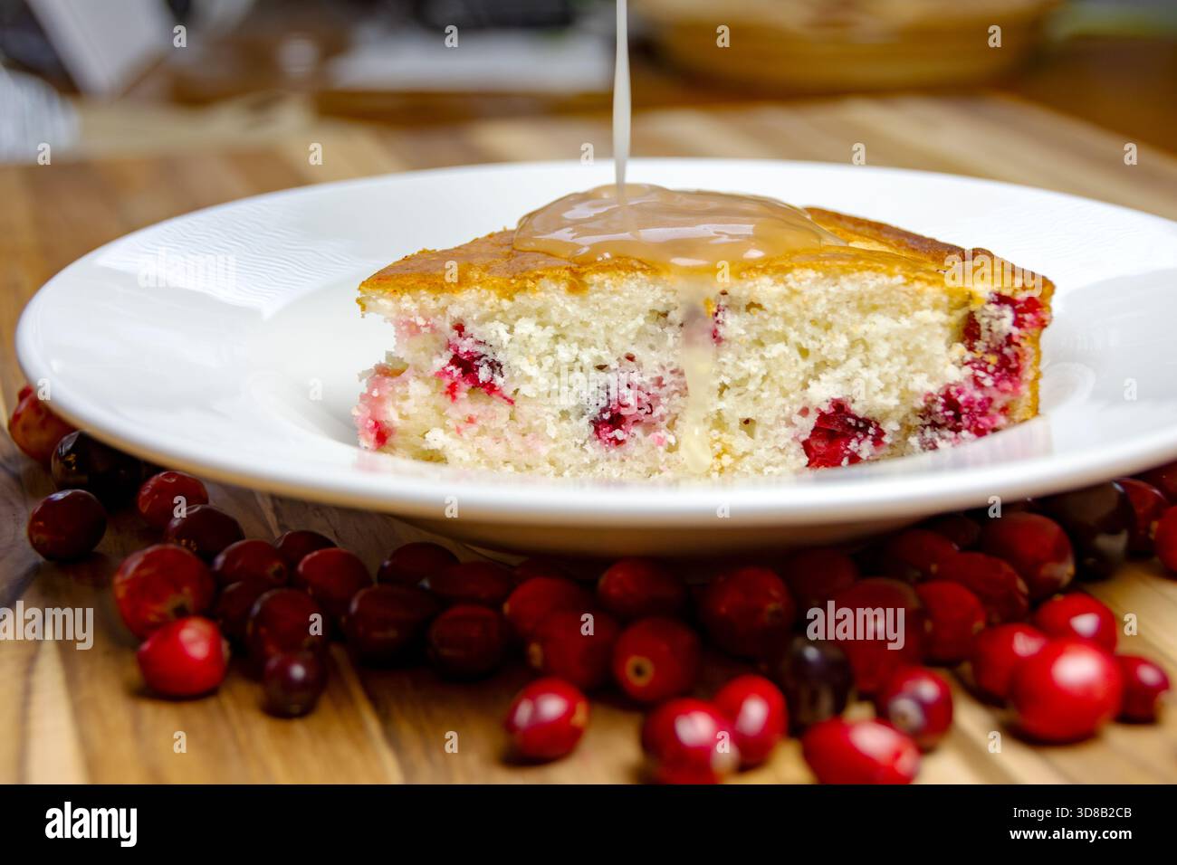 Servi une tranche de gâteau aux canneberges maison à côté du glaçage au citron, prêt pour le tir d'action crucial. Dessert sucré des fêtes. Banque D'Images