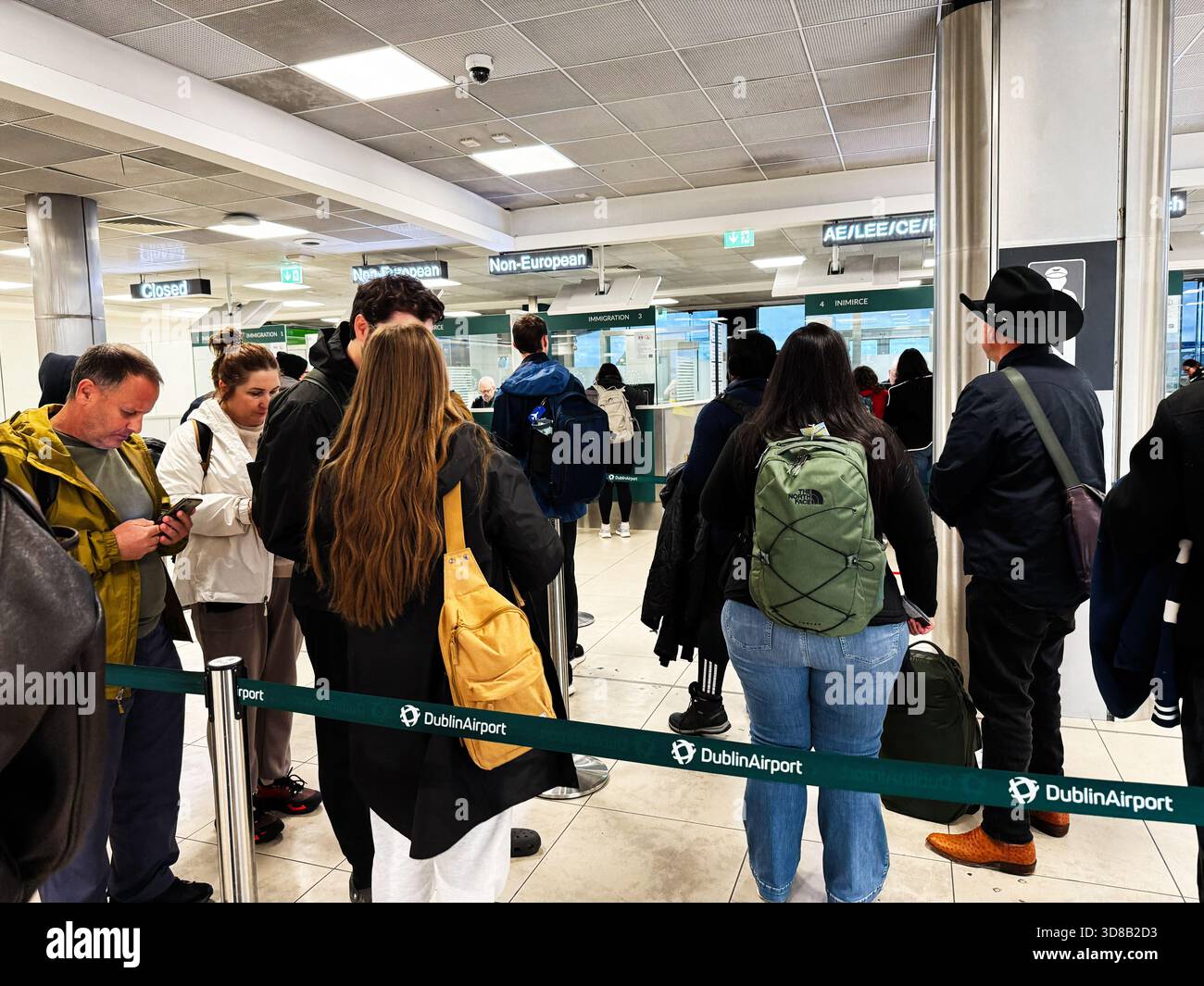 Dublin, Irlande - 21 octobre 2025 : une foule de voyageurs fait la queue aux comptoirs d'immigration de l'aéroport de Dublin avec des sacs à dos et des manteaux. Banque D'Images