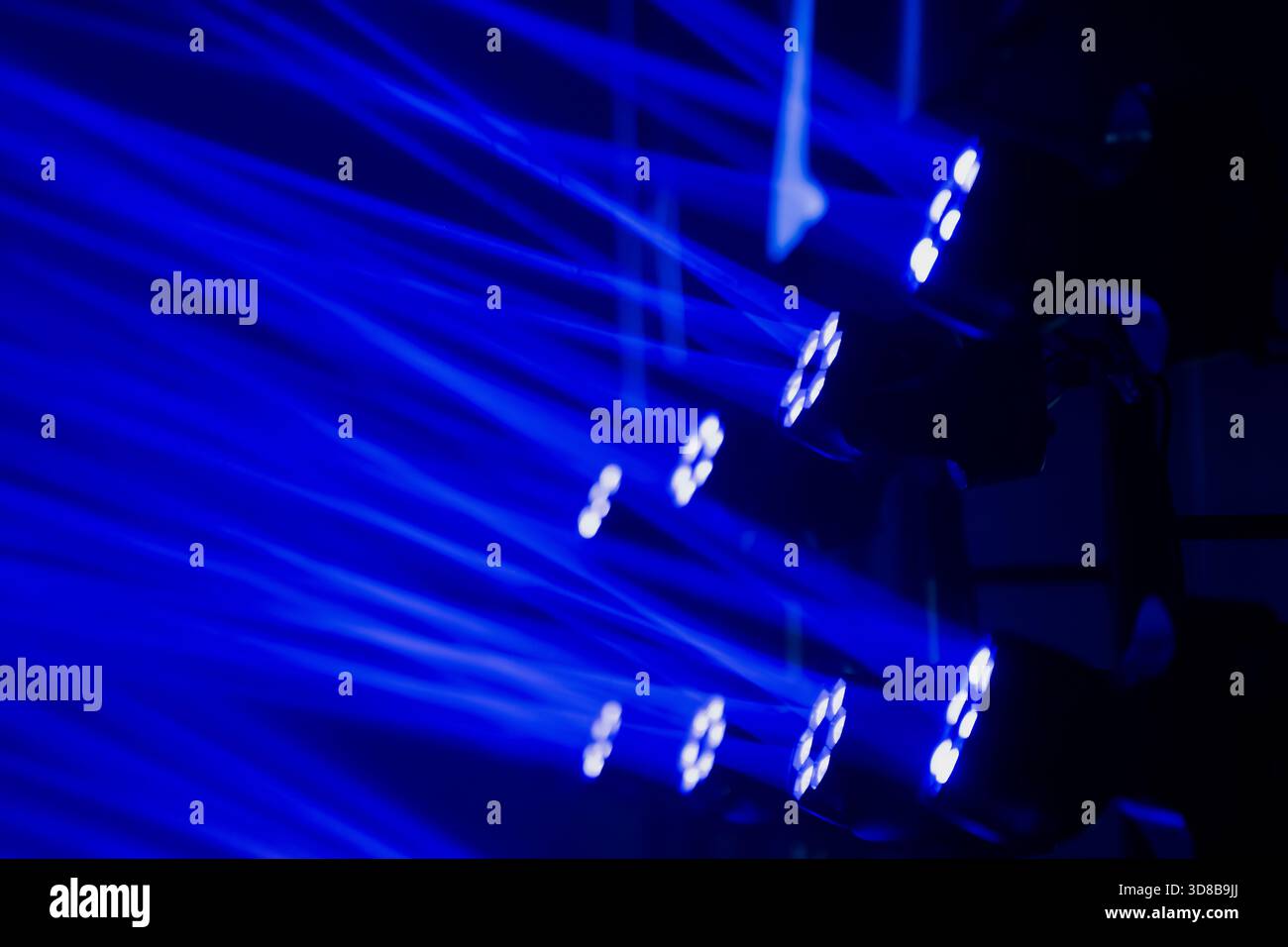 Phares mobiles LED professionnels générant des effets de faisceau bleu vif sur un écran de scène, mettant en valeur les capacités techniques dans un événement à grande échelle Banque D'Images