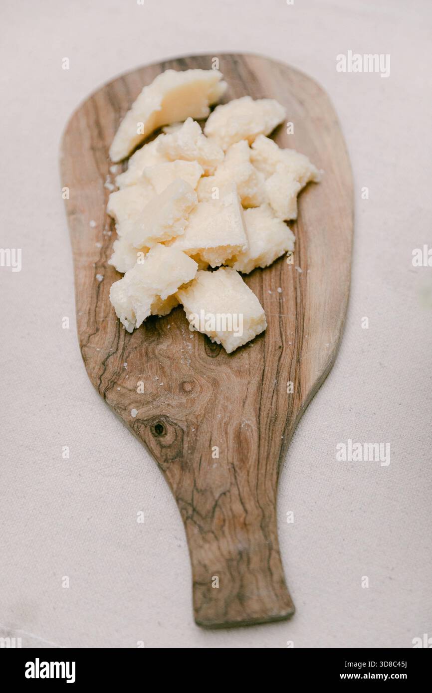 Savoureux fromage frais coupé en petits morceaux sur une planche de bois rustique, parfait pour une dégustation lors d'un rassemblement. Banque D'Images