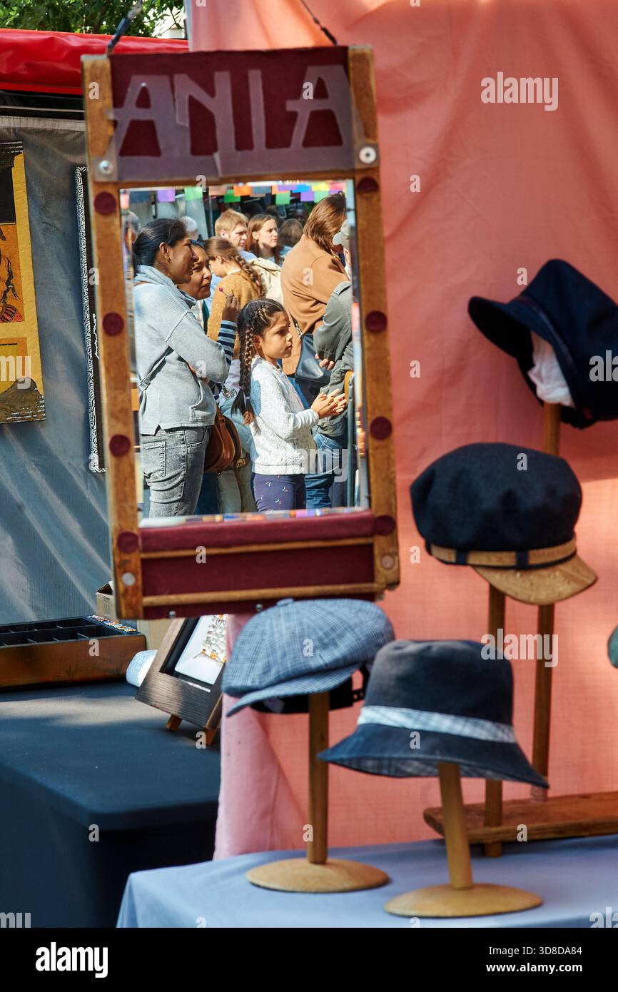 Paris, France - juin 2025 : au marché Edgar Quinet, Montparnasse, les visiteurs parcourent une variété de chapeaux tout en observant leurs reflets dans un miroir. Ceci Banque D'Images