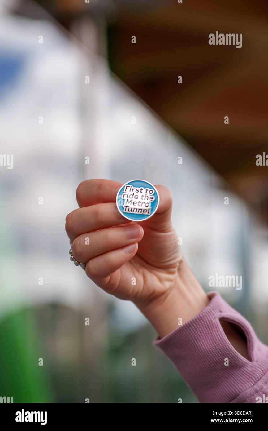 Melbourne, Victoria, Australie. 30 novembre 2025. - Gros plan de la main d'une personne montrant un badge commémoratif "premier à monter dans le tunnel de métro" sur openi Banque D'Images