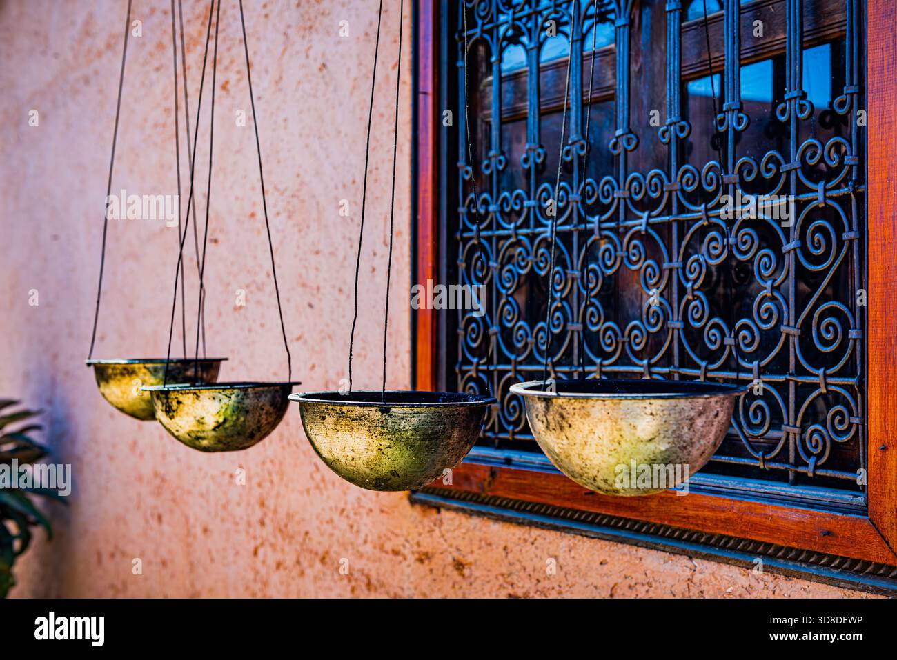 Fenêtre marocaine traditionnelle ornée de ferronnerie et de bols en laiton sur un mur en adobe rose Banque D'Images