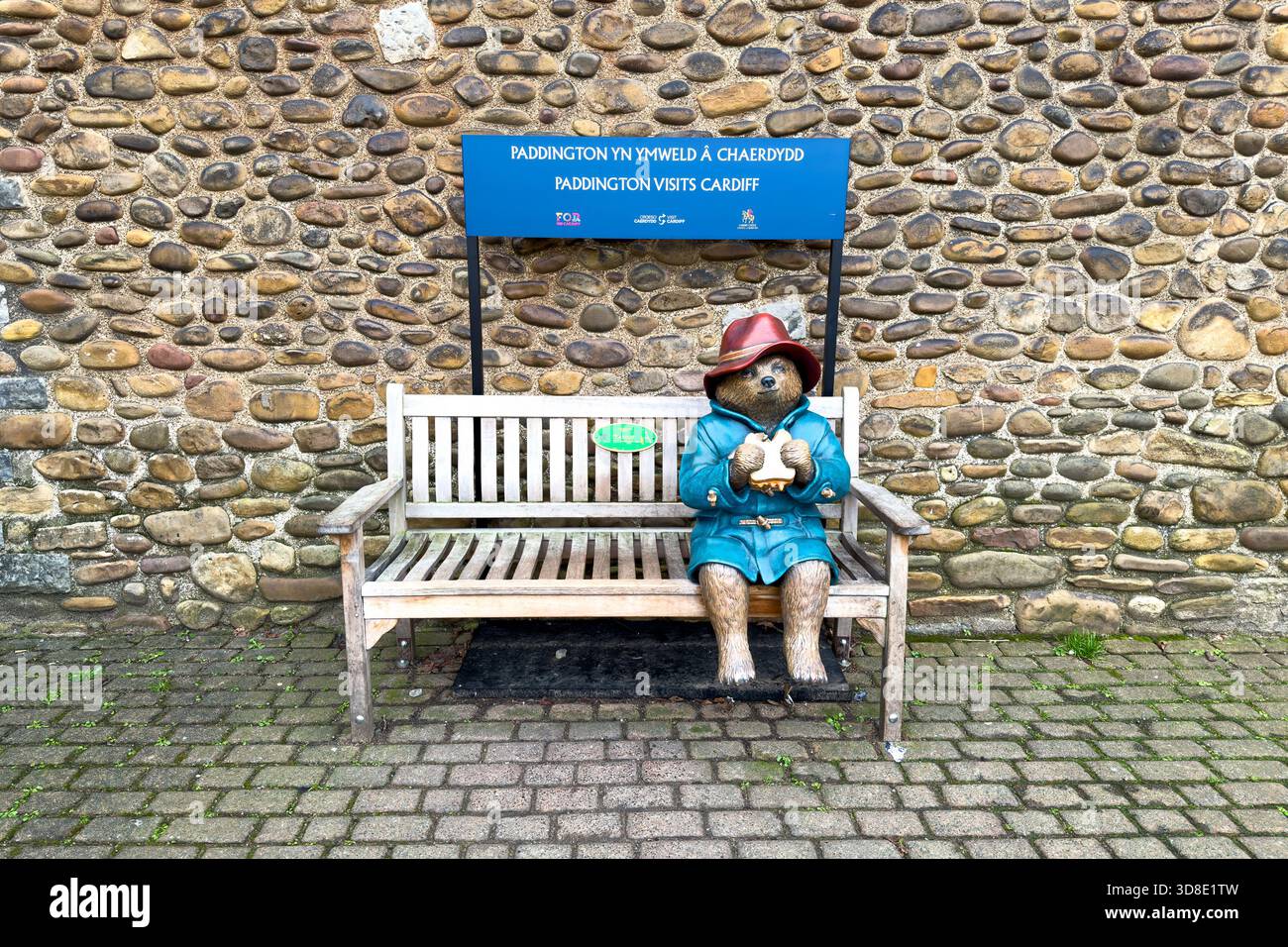 Cardiff pays de Galles - 26 novembre 2025 : L'ours de Paddington est assis sur un banc près des murs du château de Cardiff. Il mange un sandwich à la marmelade, et s'assoit d'un côté s. Banque D'Images