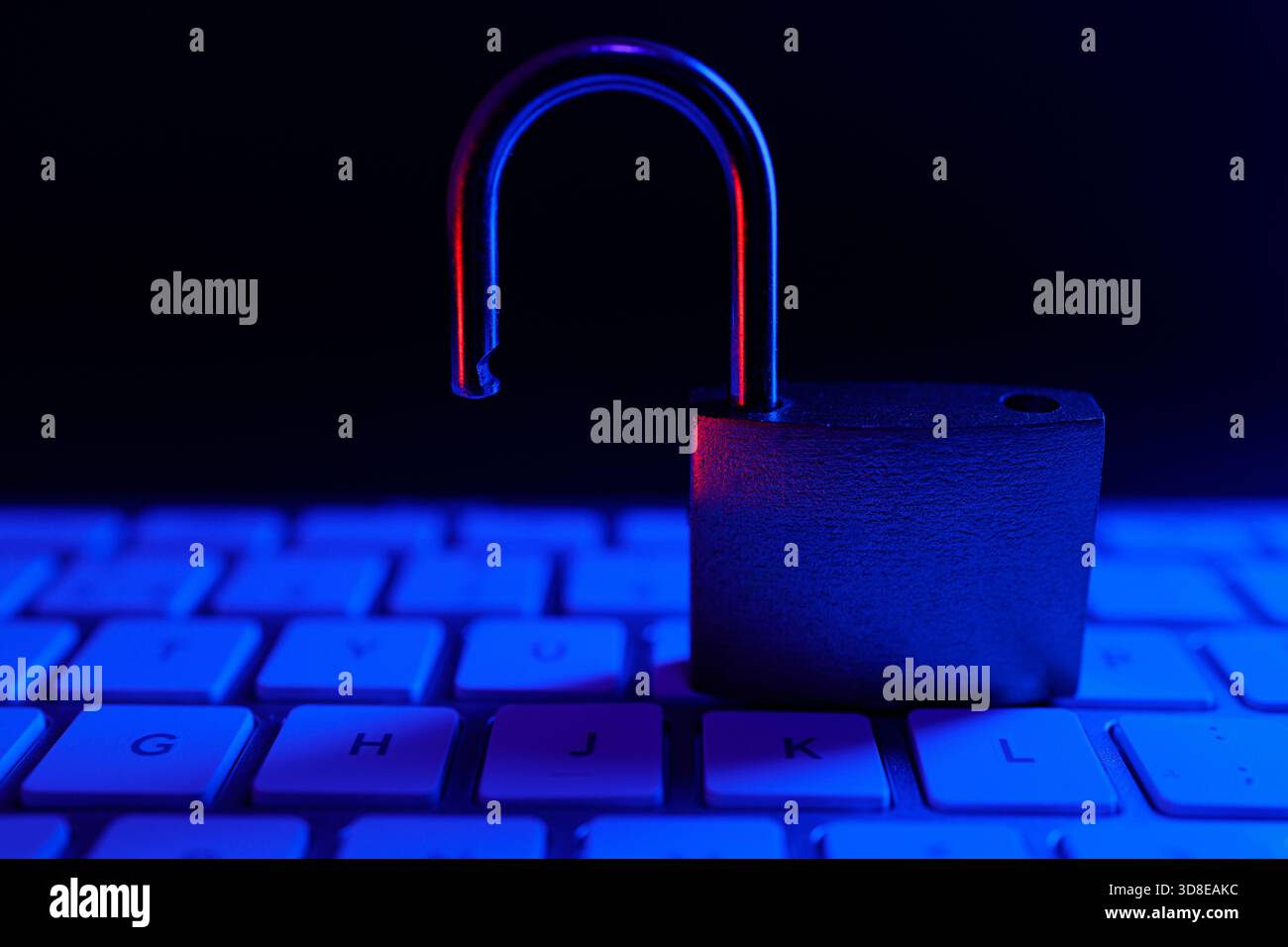 Un cadenas déverrouillé se trouve bien en évidence sur un clavier, entouré d'un éclairage bleu. Banque D'Images