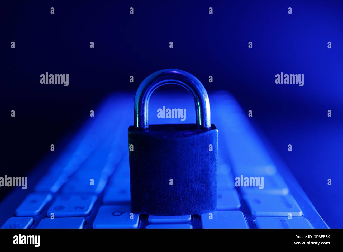 Un cadenas repose solidement sur un clavier, entouré d'une lueur bleue. Cette scène souligne le rôle crucial de la cybersécurité dans la protection des données en ligne Banque D'Images