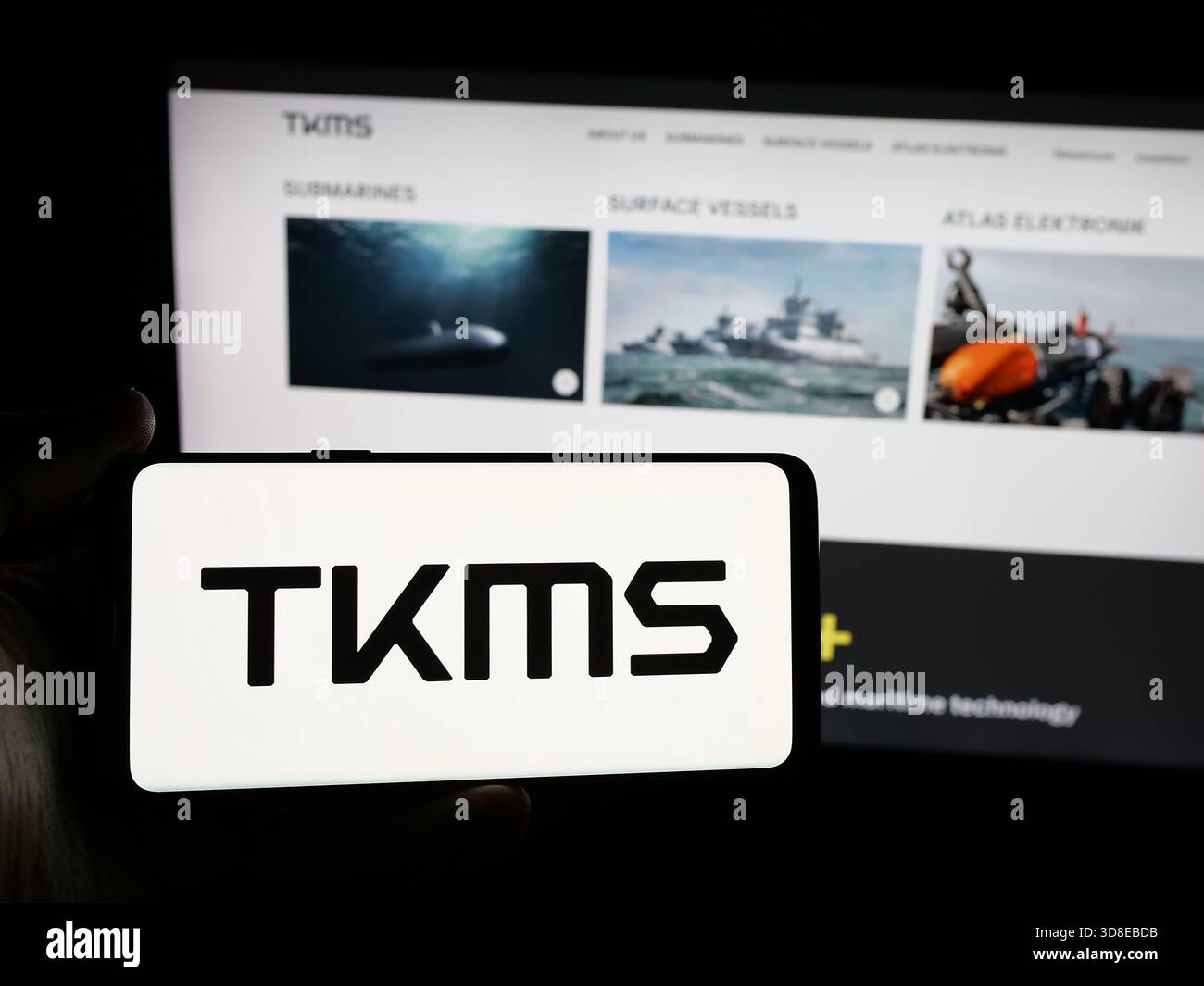 Stuttgart, Allemagne - 11-20-2025 : personne tenant un smartphone avec le logo de la société ThyssenKrupp Marine Systems (TKMS) sur l'écran en face du site Web. Banque D'Images