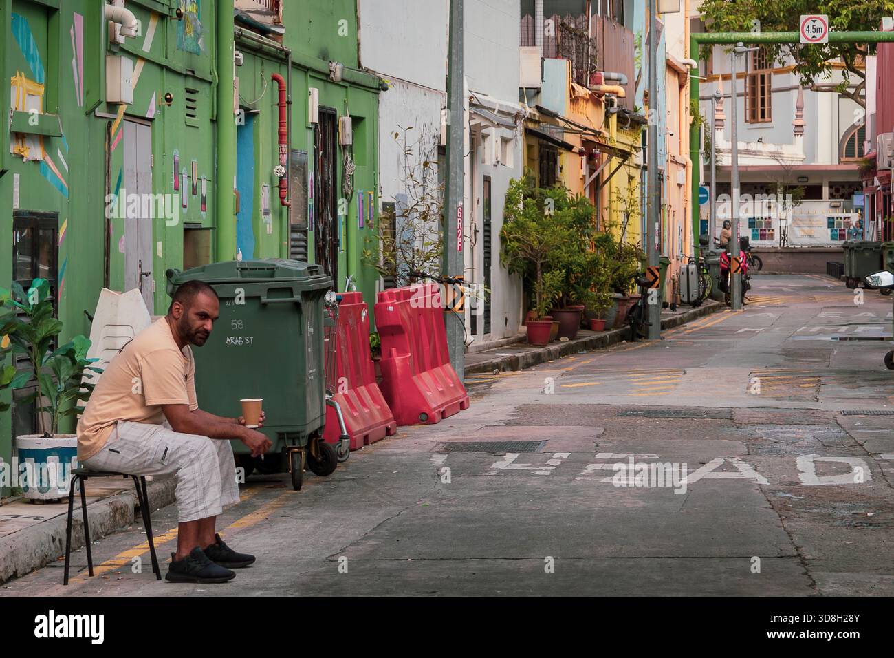 Gars assis sur une chaise dans une ruelle à Kampong Glam, Singapour Banque D'Images