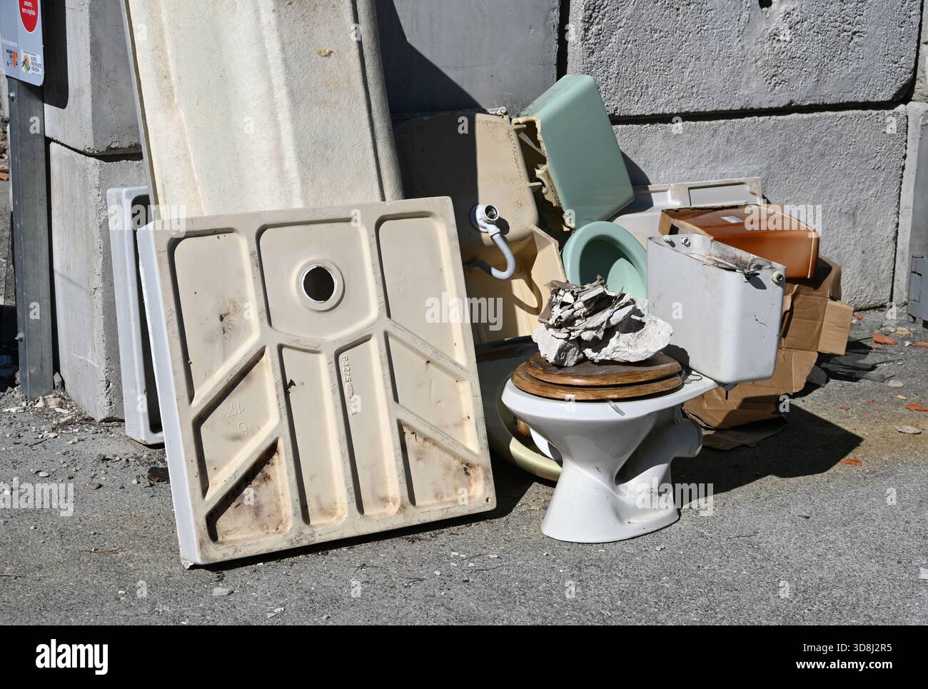 Vieille toilette, accessoires de salle de bains jetés et base de douche dans la décharge municipale ou le centre d'élimination des déchets Banque D'Images
