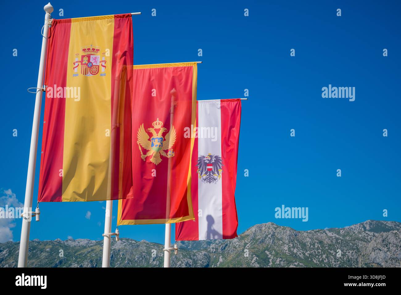 Trois drapeaux agitant au vent contre un ciel bleu clair. Banque D'Images