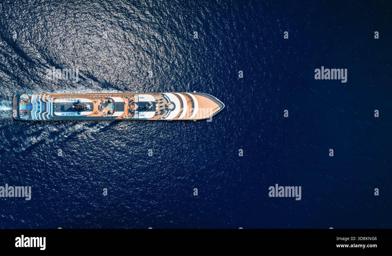 Vue aérienne aérienne d'un bateau de croisière de luxe ou d'un yacht de luxe naviguant au-dessus de l'océan bleu étincelant comme concept de voyage avec espace de copie< Banque D'Images