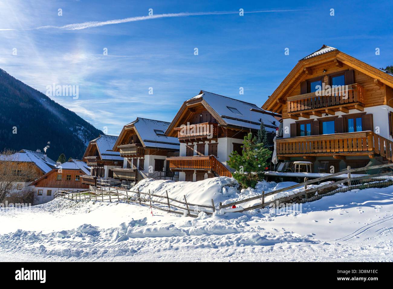 Chalets alpins enneigés sous un soleil d'hiver éclatant avec des montagnes en arrière-plan Banque D'Images
