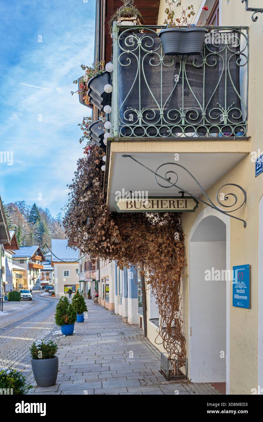 Garmisch-Partenkirchen, Allemagne – 28 novembre 2025. Un panneau de bibliothèque pittoresque "BÜCHEREI" est suspendu sous un balcon vintage avec des vignes grimpantes séchées et wi Banque D'Images