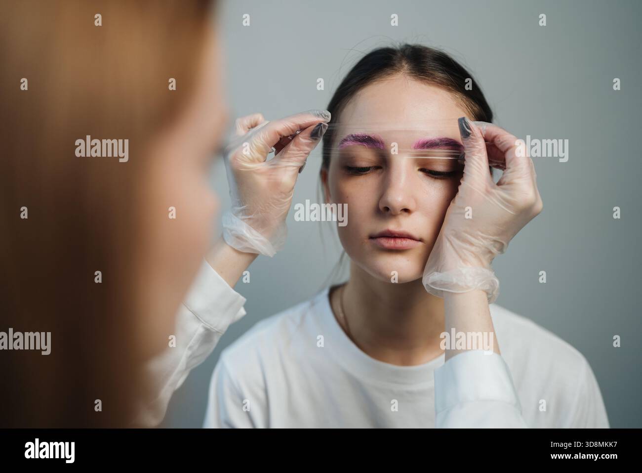 femme subissant un traitement professionnel des sourcils, femme qualifiée appliquant des soins post-calmants aux sourcils Banque D'Images