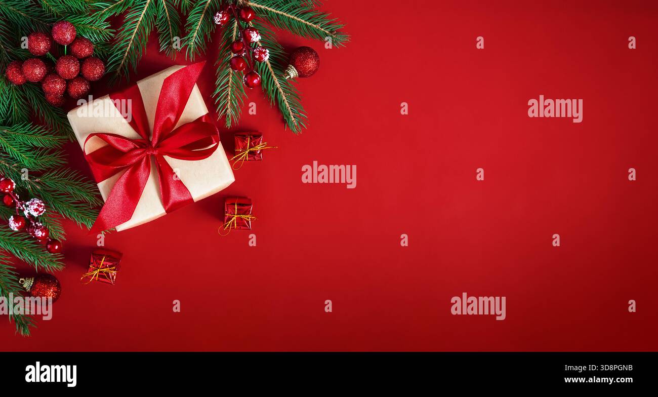 Fond de vacances joyeux Noël. Fond plat rouge de Noël avec boîte-cadeau, branches de sapin et décorations de vacances. Banque D'Images