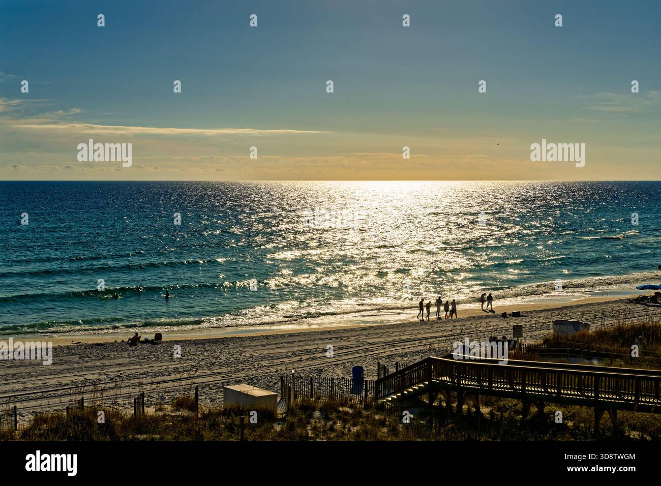 Les gens marchant sur une plage côtière du golfe d'Amérique Floride près de destin, Floride USA, près du coucher du soleil. Banque D'Images
