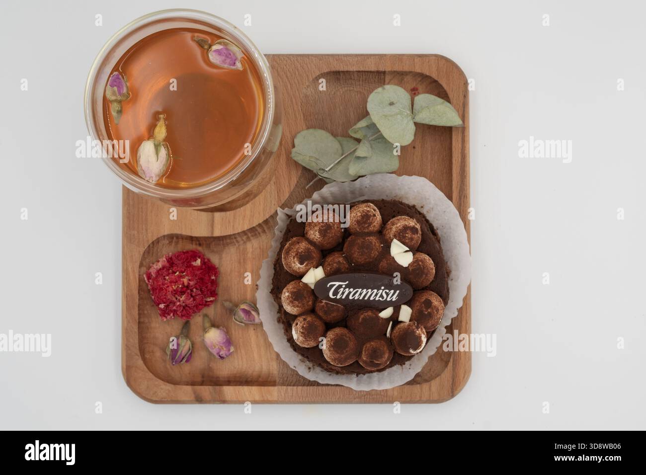 Dessert tiramisu avec tisane sur plateau en bois avec fleurs séchées et feuilles d'eucalyptus sur un fond blanc propre Banque D'Images