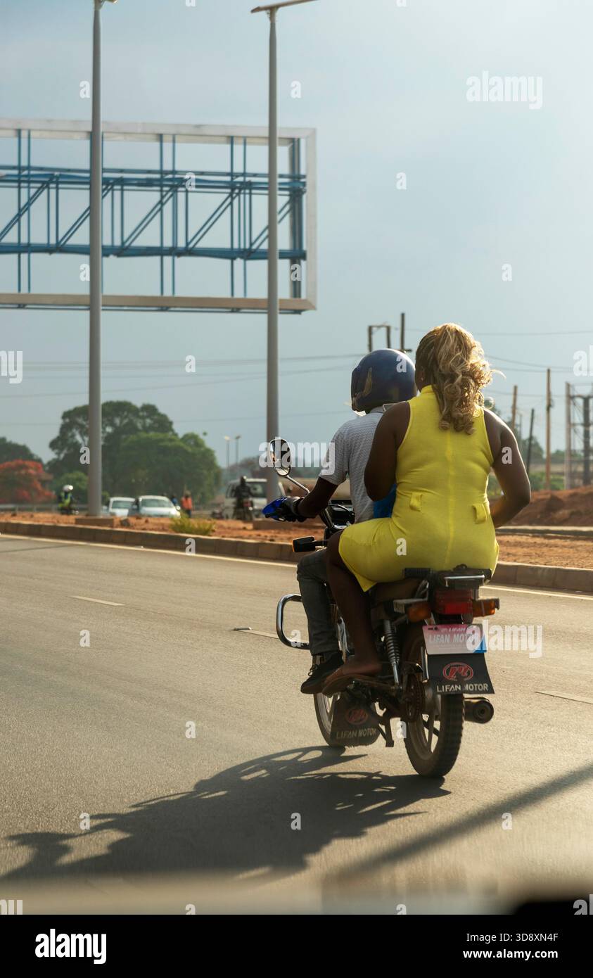 Lilongwe Malawi Afrique. 08.11.2025. Taxi-coursier à moto transportant une femme sur une autoroute urbaine à Lilongwe Malawi Afrique. Banque D'Images
