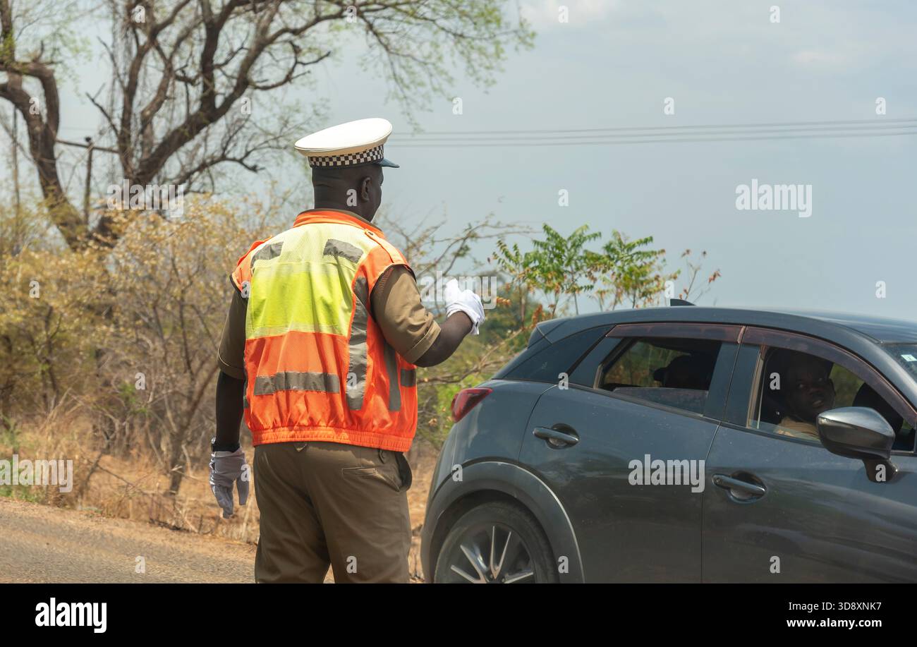 Malawi SSouthern Africa. 19.11.2025. Un agent de la circulation en uniforme et portant des gants blancs signale à un automobiliste de s'arrêter. Banque D'Images