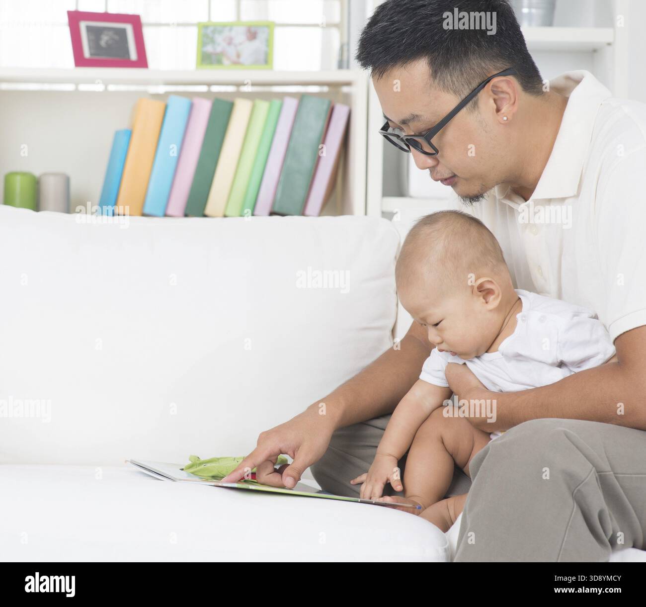Style de vie familial asiatique à la maison. Père et enfant lisant livre d'histoire sur le canapé Banque D'Images