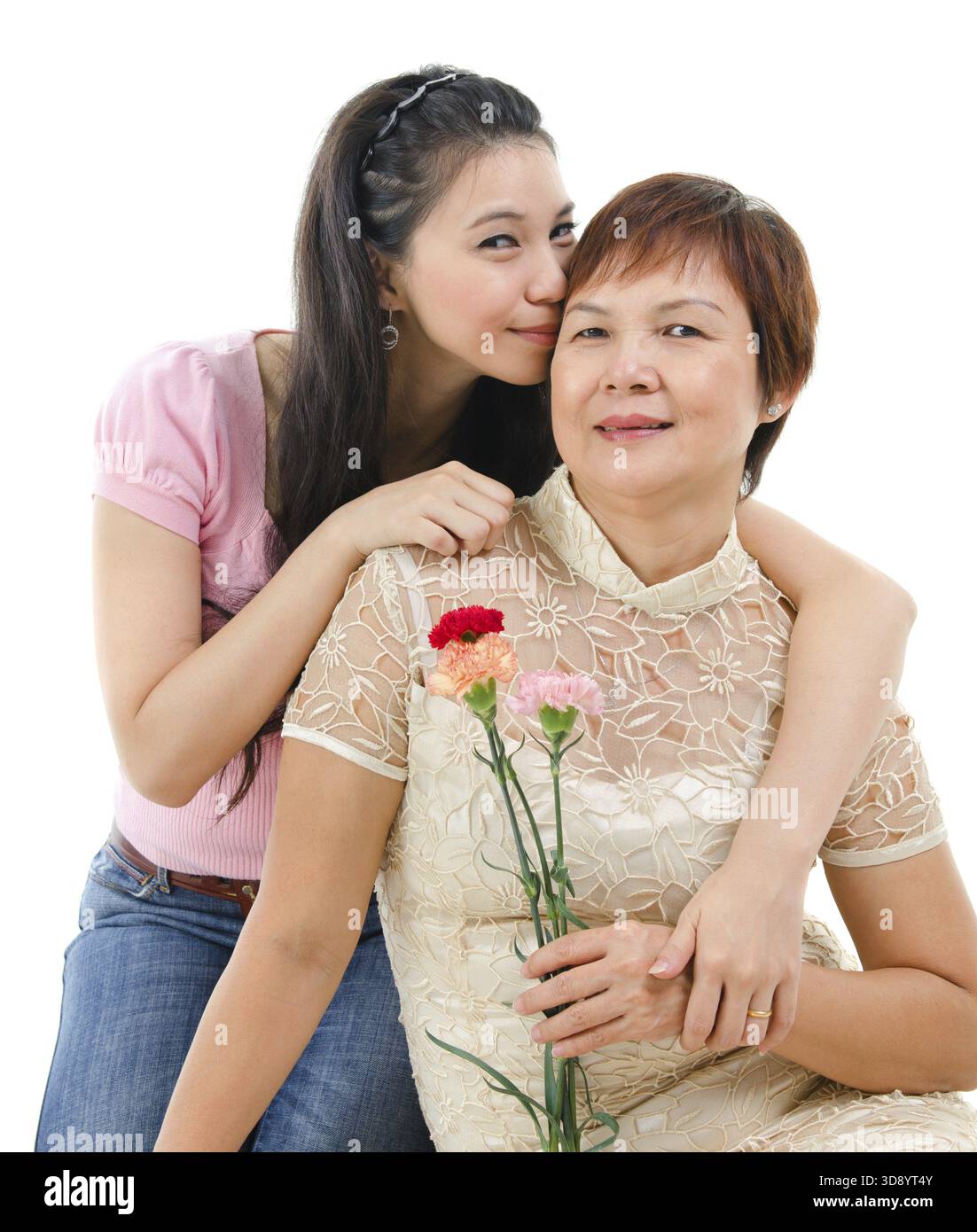 Mère âgée tenant la fleur d'oeillet, fille adulte embrasse et embrasse maman, isolée sur fond blanc. Portrait de famille asiatique mixte Banque D'Images
