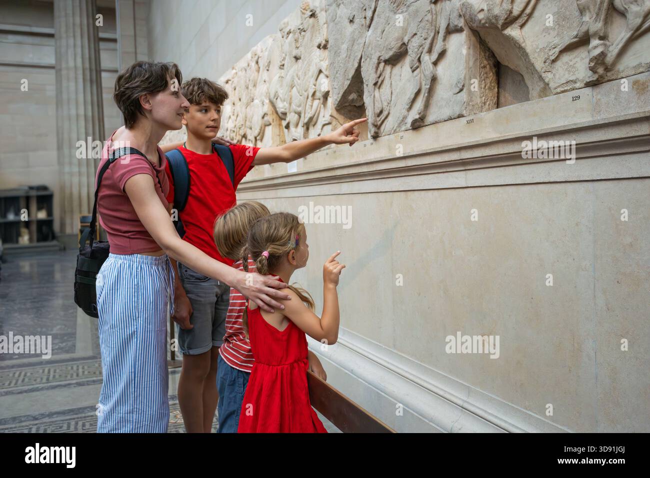La famille captivée admire les sculptures historiques détaillées dans le musée Banque D'Images