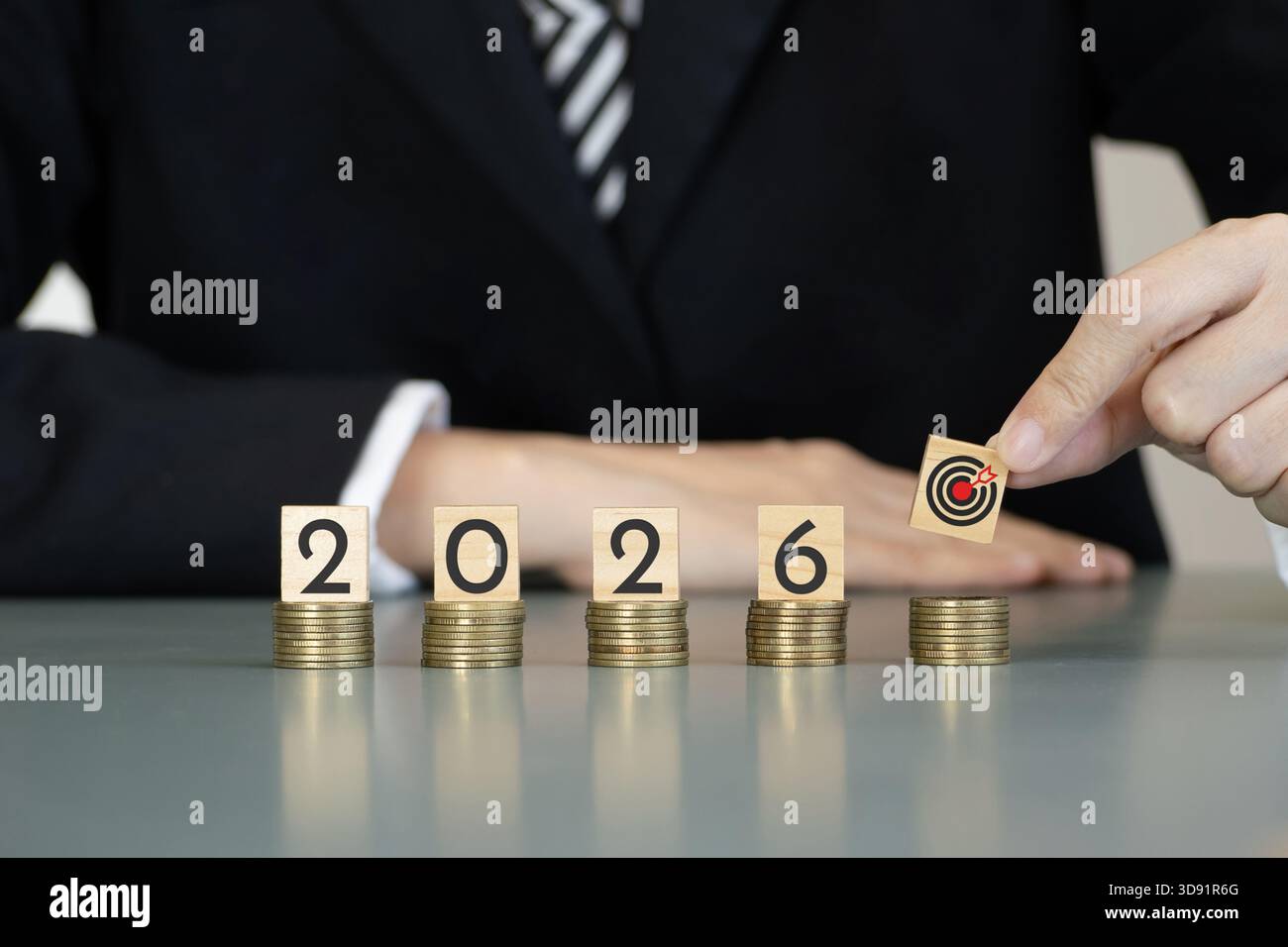 les gens d'affaires placent un bloc cible sur des piles de pièces à côté du numéro de l'année 2026 sur des cubes en bois, symbolisant la stratégie d'investissement, le plan financier Banque D'Images