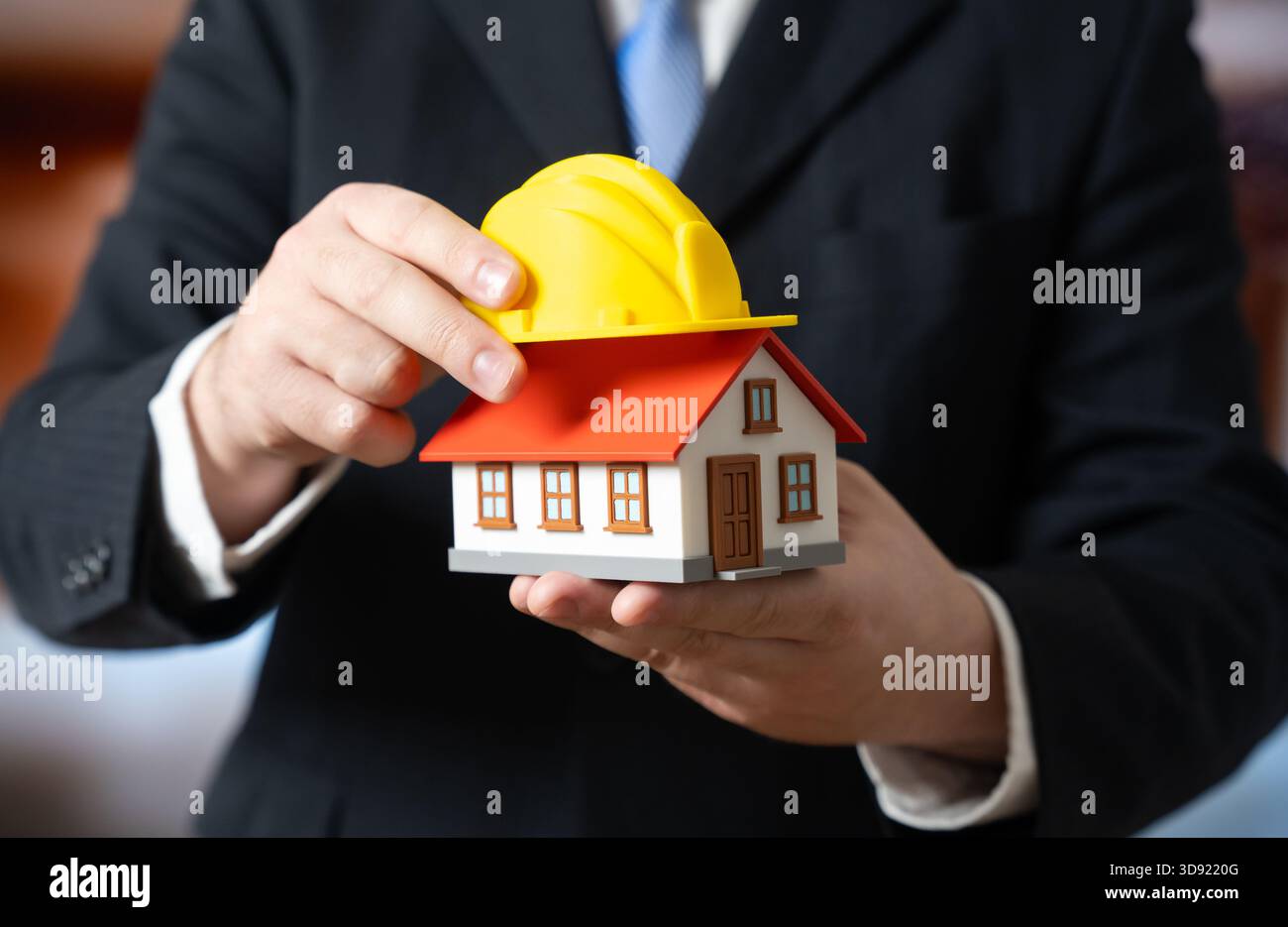 Un homme d'affaires pose un casque jaune sur une maison. Le projet de rénovation commence. La planification de la construction, la budgétisation de la réparation de la maison et l'immobilier se développent Banque D'Images