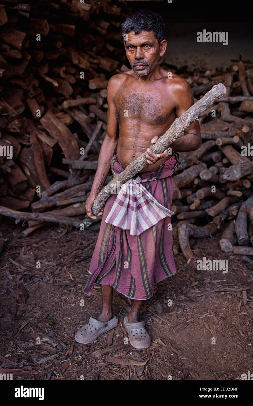 Portrait d'un homme travaillant à fournir du bois pour le terrain de crémation à Swargadwar, Puri, Odisha, Inde Banque D'Images