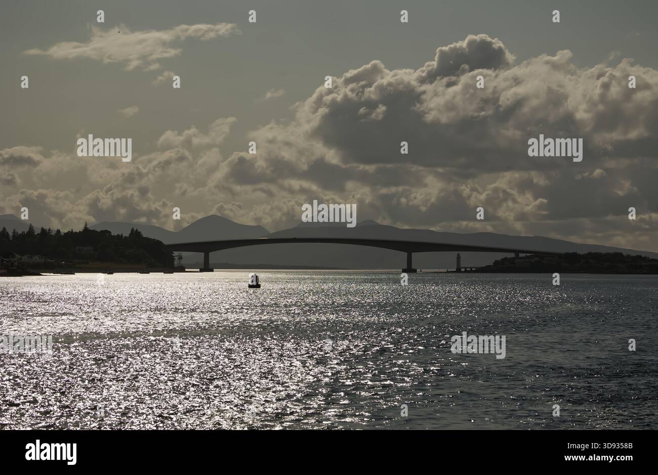 Vue rétroéclairée du pont Skye sur le Kyle de Lochalsh, en Écosse, photographiée depuis un bateau sous les nuages et le ciel dégagé. Banque D'Images