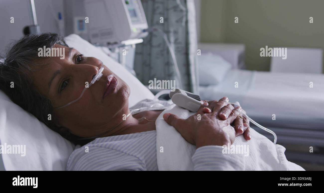 Femme âgée au repos allongée dans le lit d'hôpital, dans le dessus rayé avec canule nasale et oxymètre de pouls Banque D'Images