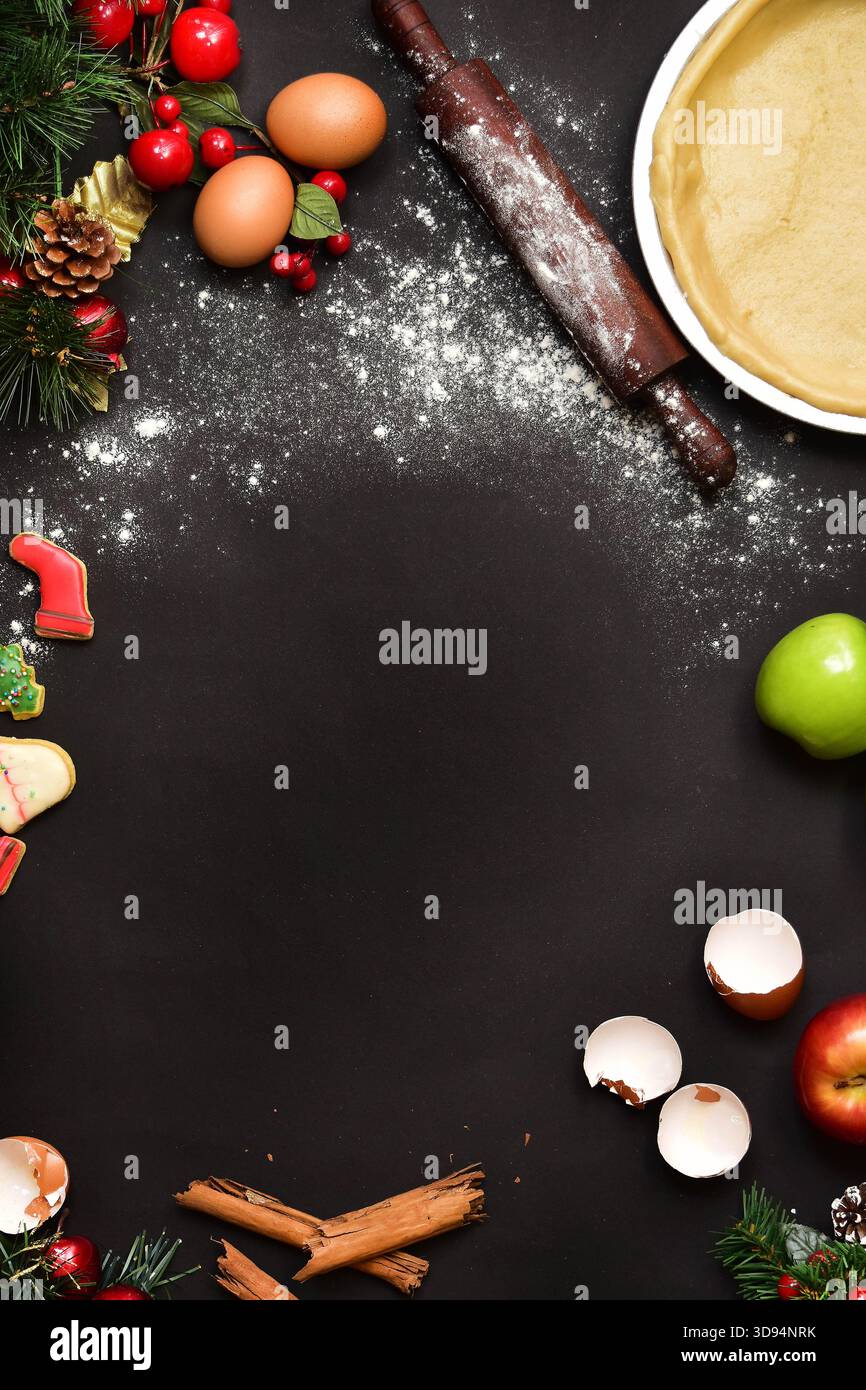 Une couche plate de haut en bas, sombre et festive montrant le processus de cuisson des fêtes, avec un cadre central de farine dispersée, entouré d'ingrédients, un bois Banque D'Images