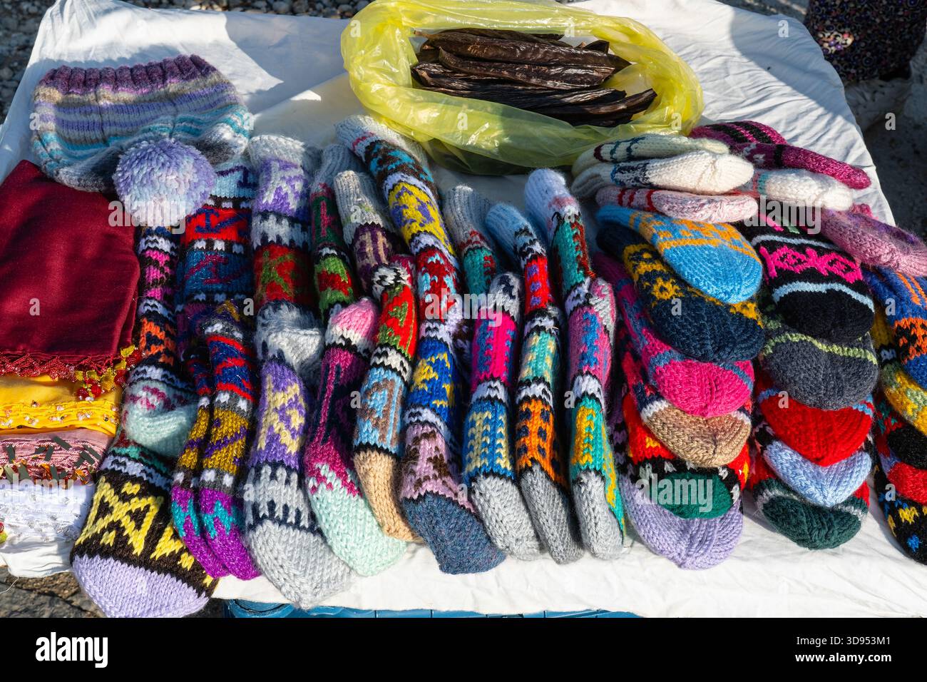 Chaussettes en laine tricotées à la main aux couleurs vives, à motifs et un sac de haricots de caroube exposés sur un stand en bord de route. Banque D'Images