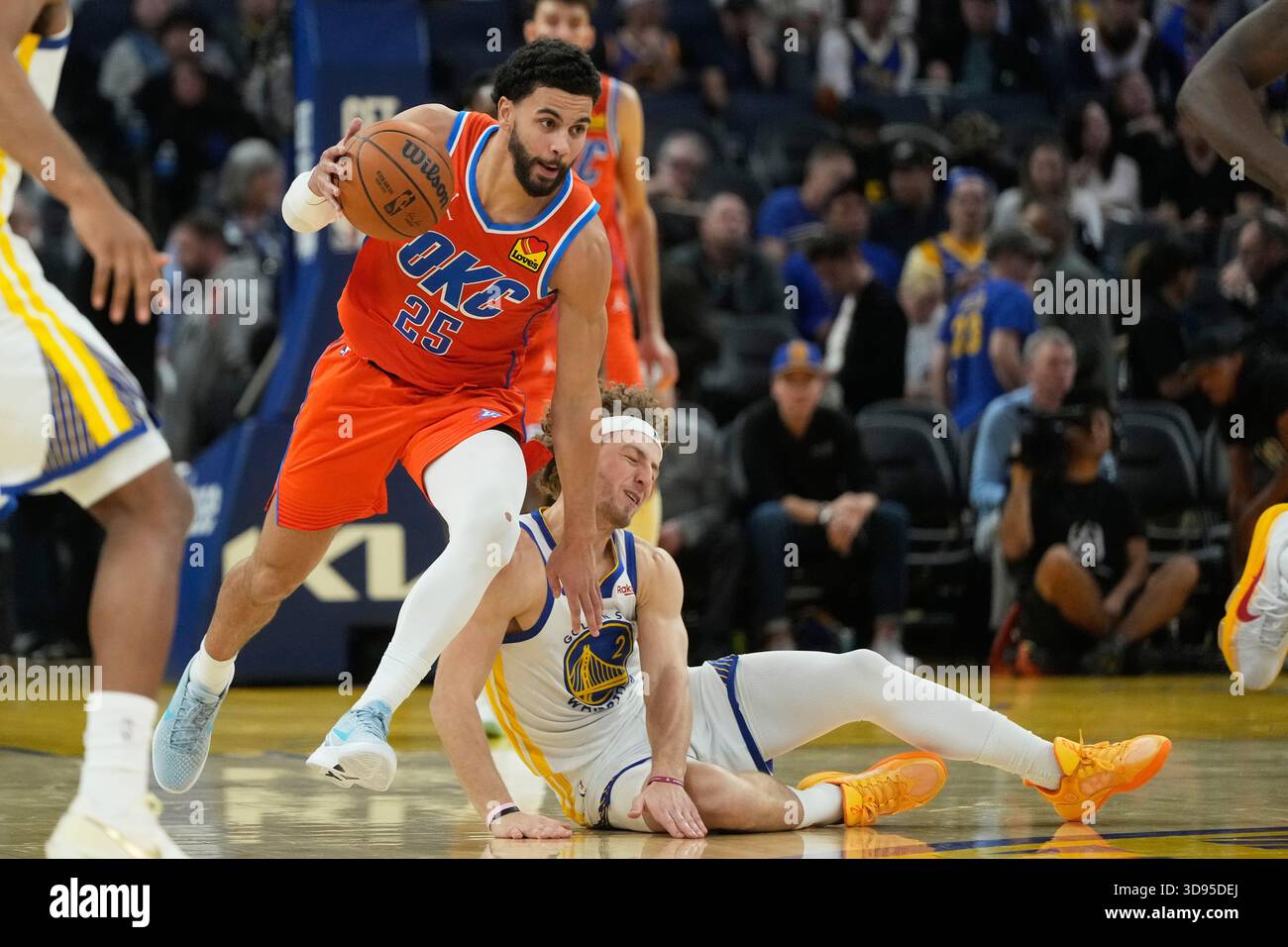 Oklahoma City Thunder guard Ajay Mitchell (25) brings the ball up the court against Golden State Warriors guard Brandin Podziemski, bottom, during an NBA basketball game in San Francisco, Tuesday, Dec. 2, 2025. (AP Photo/Jeff Chiu) Banque D'Images
